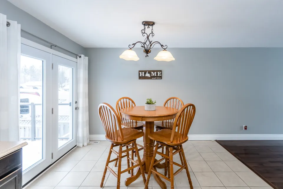 An eat-in kitchen with a round wooden table and light blue-grey walls