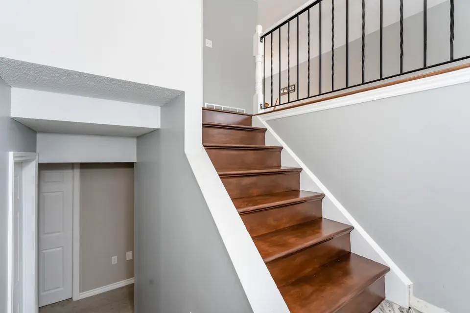A hallway and staircase with wood stairs and crisp white walls