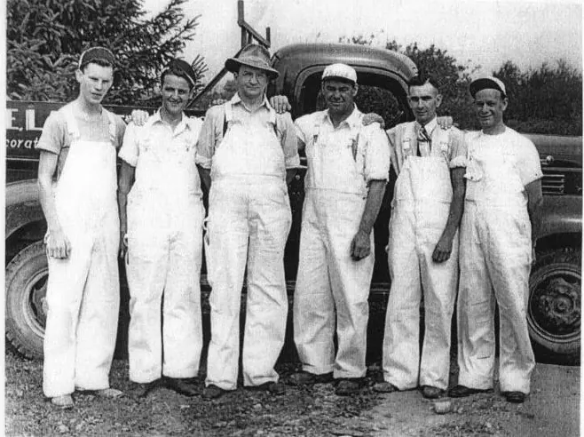 The original Lackey Decorating crew in white painter's overalls, standing in front of a vintage truck