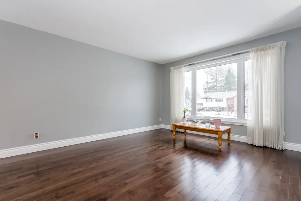 A living room repainted in a light neutral with bright windows